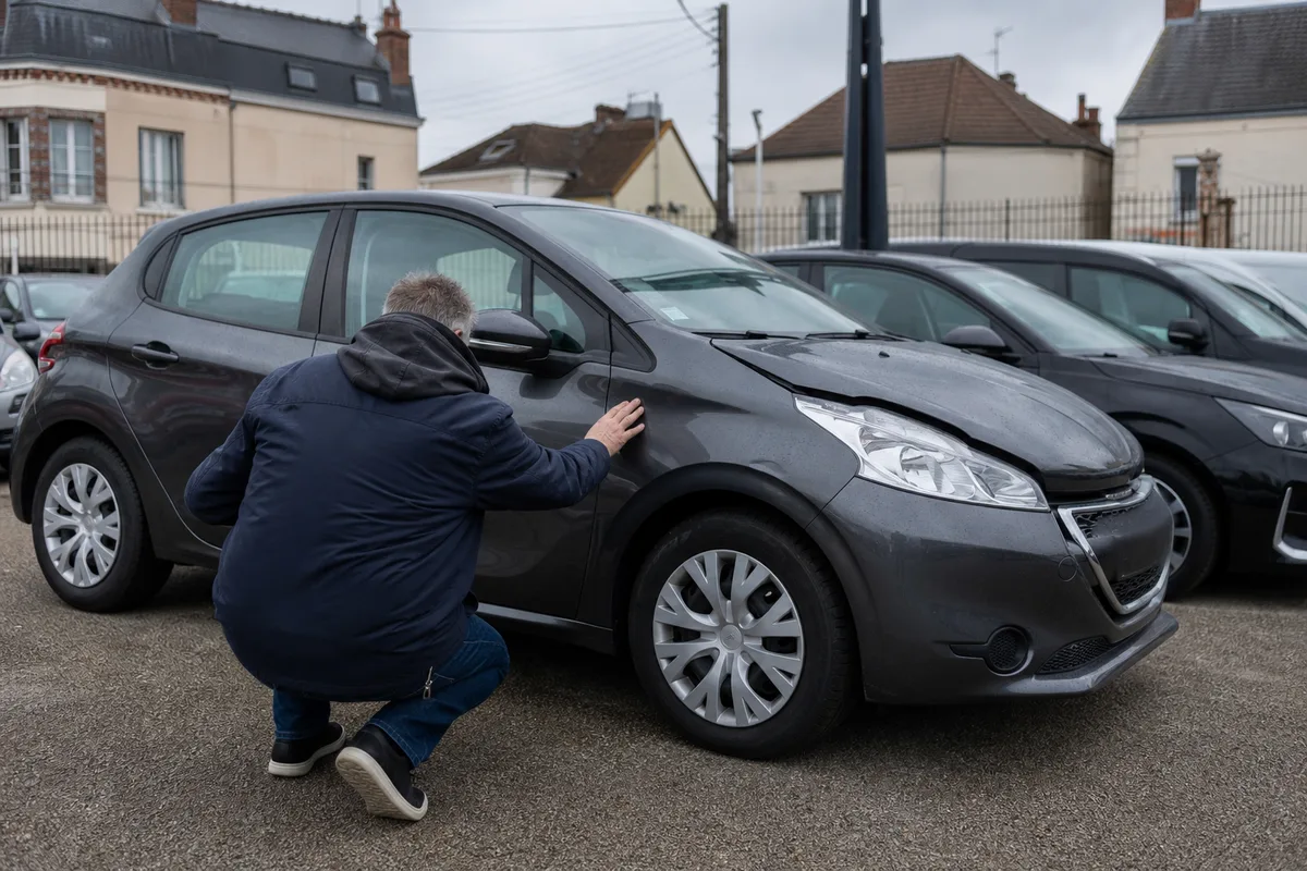 Jeune conductrice inspectant une citadine d&rsquo;occasion avant achat