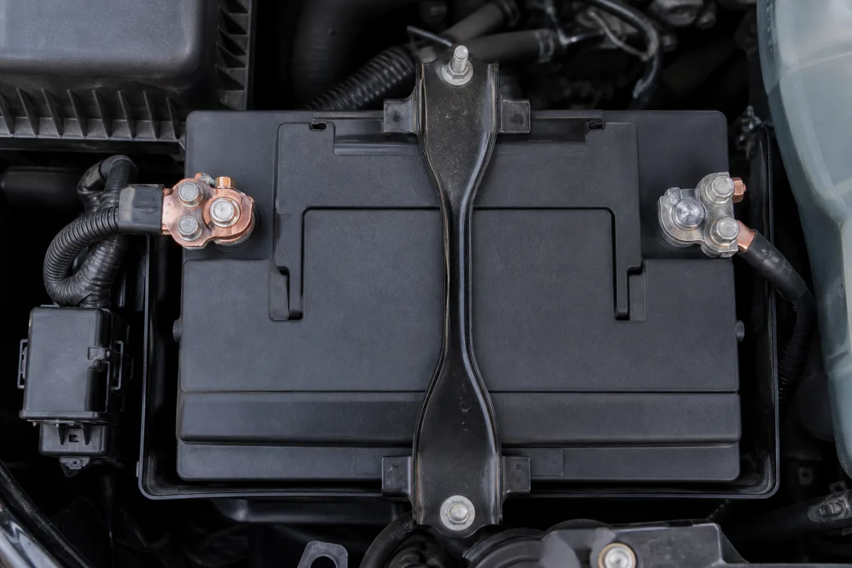 Batterie de voiture 12 volts vue de dessus dans un compartiment moteur, bornes visibles